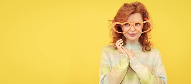 Woman isolated face portrait, banner with copy space. fashion model. pretty lady on yellow background. funny redhead woman in party glasses - Fotografie, Obrázek