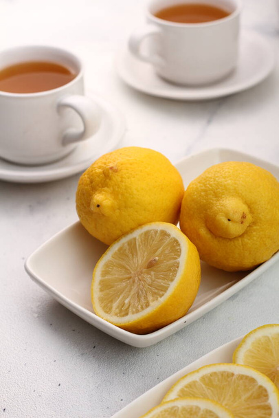 thé au citron avec tasse de fruits aromatiques sur table blanche. - Photo, image