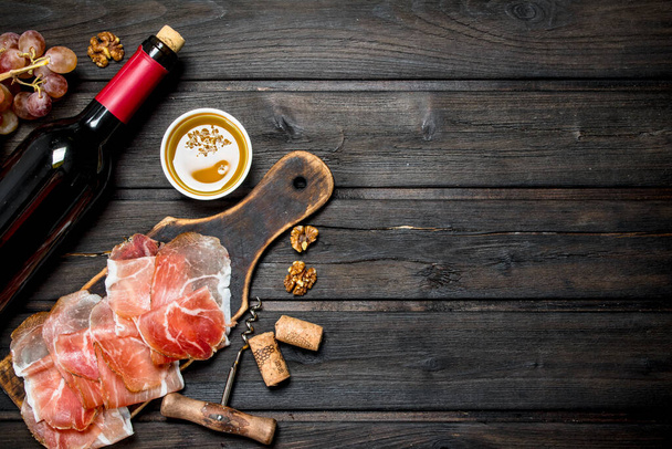 Traditional Spanish ham with red wine. On a wooden background. - Foto, afbeelding
