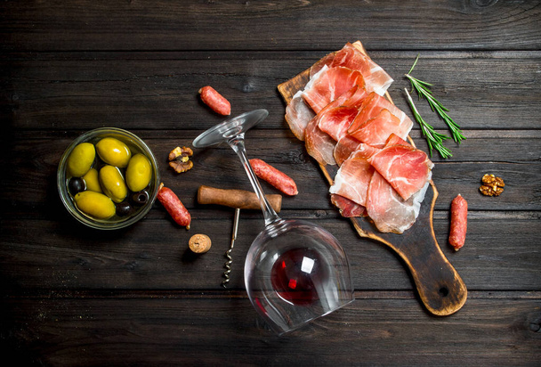 Spanish ham with red wine and nuts. On a wooden background. - Foto, Imagem