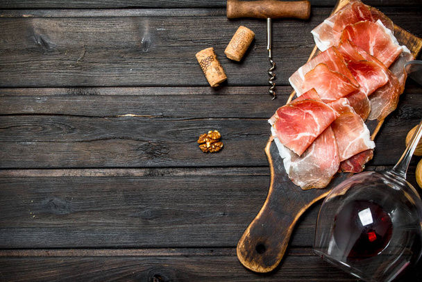 Spanish ham with red wine and nuts. On a wooden background. - Фото, зображення