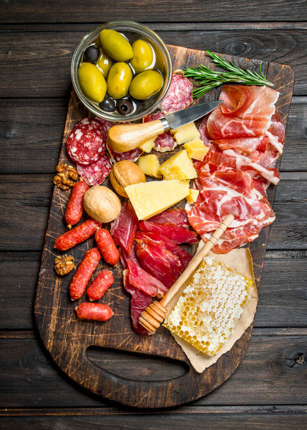 Antipasto background. Assortment of meat snacks on the Board with olives and Parmesan. On a wooden background. - Foto, Bild