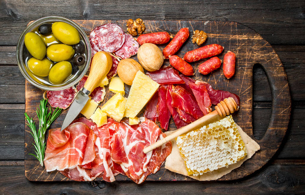 Antipasto background. Assortment of meat snacks on the Board with olives and Parmesan. On a wooden background. - Foto, immagini
