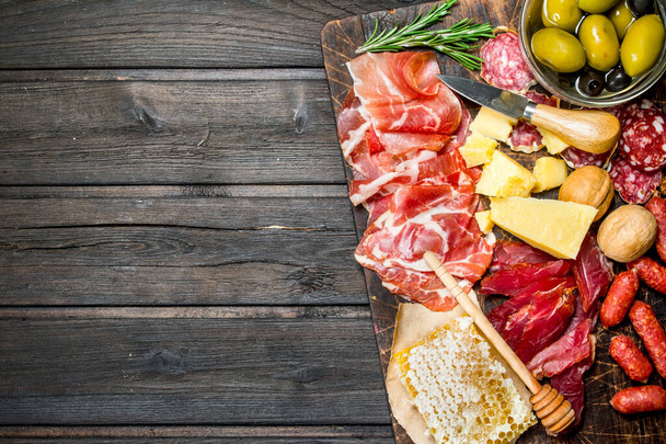 Antipasto background. Assortment of meat snacks on the Board with olives and Parmesan. On a wooden background. - Valokuva, kuva