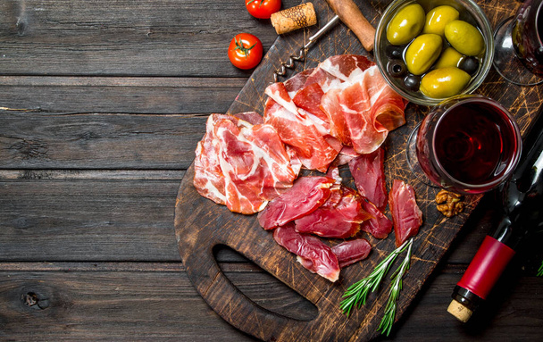 Antipasto background. Different meat snacks with red wine. On a wooden background. - Zdjęcie, obraz