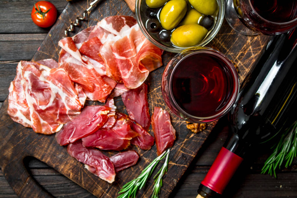 Antipasto background. Different meat snacks with red wine. On a wooden background. - Fotografie, Obrázek
