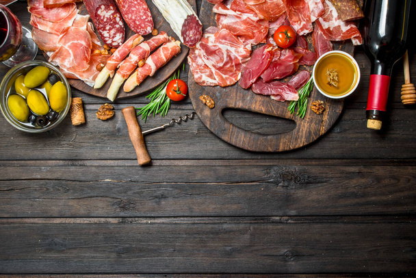 Antipasto background. Different meat snacks with red wine. On a wooden background. - Zdjęcie, obraz