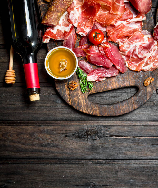 Antipasto background. Different meat snacks with red wine. On a wooden background. - Foto, Imagen