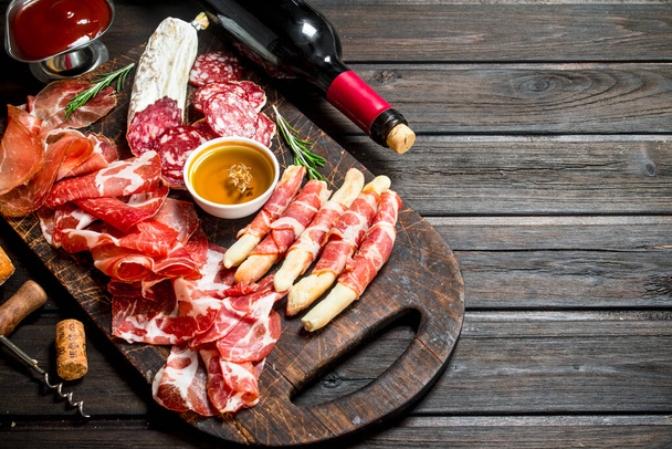 Antipasto background.Italian meat appetizers with red wine. On a wooden background. - Photo, Image
