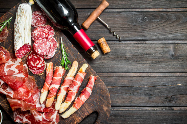 Antipasto background.Italian meat appetizers with red wine. On a wooden background. - Фото, изображение