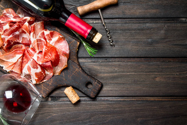Spanish ham with a glass of red wine. On a wooden background. - Foto, afbeelding