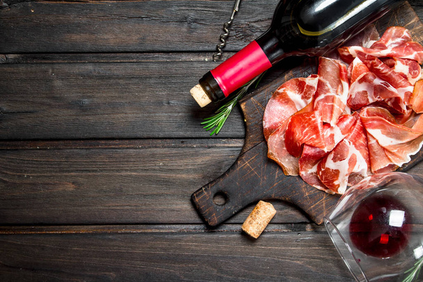 Spanish ham with a glass of red wine. On a wooden background. - Zdjęcie, obraz
