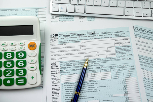 Blank 1040 US Indywidualny formularz zwrotu podatku dochodowego 2022 z kalkulatorem pióra i klawiaturą komputerową. Koncepcja papierkowej roboty ostatecznej - Zdjęcie, obraz