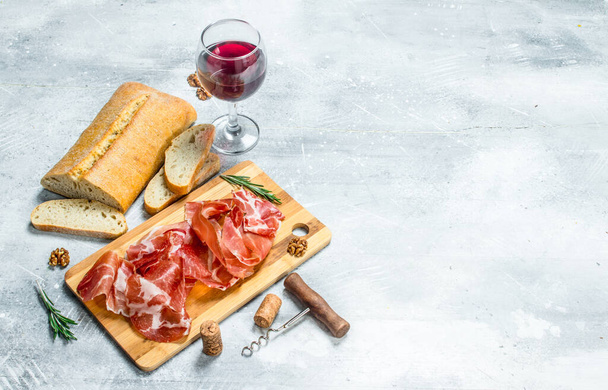 Traditional Spanish ham with ciabatta and red wine. On a rustic background. - Photo, Image