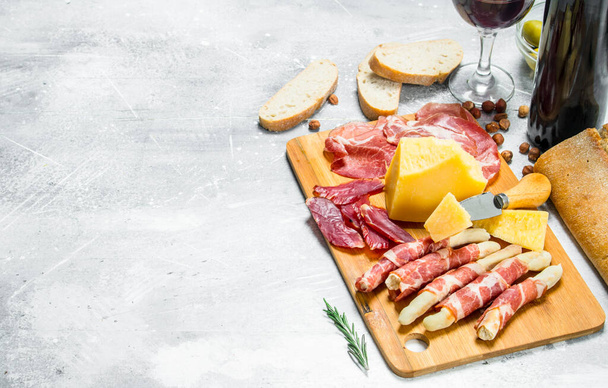 Antipasto background. Various meat and cheese snacks with red wine. On a rustic background. - Foto, Imagen