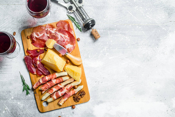 Antipasto background. Various meat and cheese snacks with red wine. On a rustic background. - Photo, Image