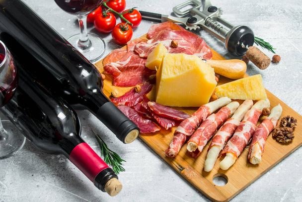 Antipasto background. Various meat and cheese snacks with red wine. On a rustic background. - Photo, image