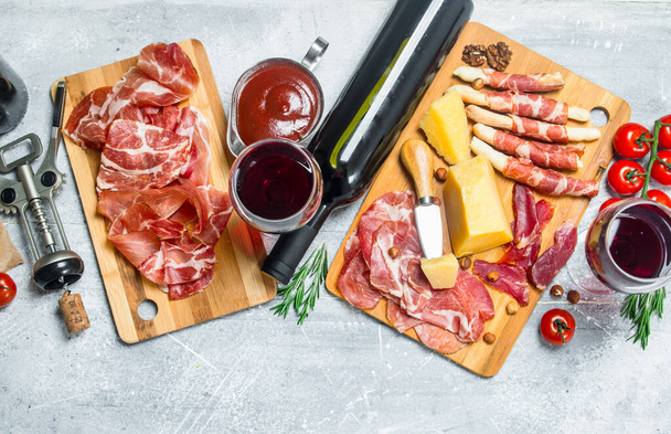 Antipasto background. Various meat and cheese snacks with red wine. On a rustic background. - Foto, afbeelding