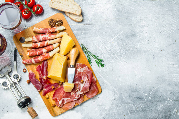 Antipasto background. Various meat and cheese snacks with red wine. On a rustic background. - Zdjęcie, obraz