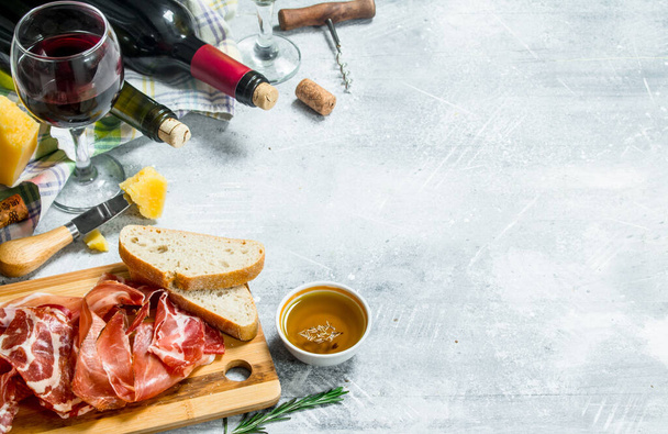 Antipasto background. Red and white wine with meat and cheese appetizers. On a rustic background. - Foto, Imagen