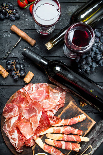 Antipasto background.Traditional Italian appetizers with red wine. On black rustic background. - Фото, изображение