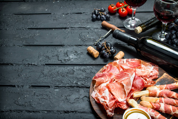 Antipasto background.Traditional Italian appetizers with red wine. On black rustic background. - Фото, зображення