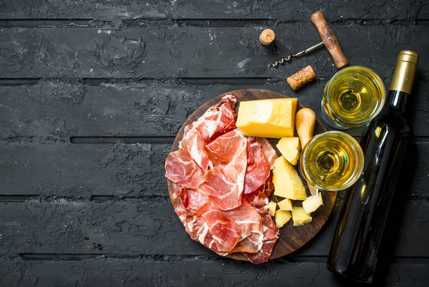 Antipasto background.Italian appetizers with white wine. On black rustic background. - Foto, Imagen