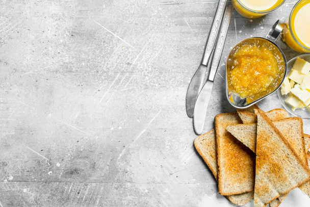 Toasted bread with butter and orange jam. On a rustic background. - Foto, afbeelding