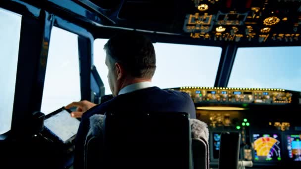 der Pilot hält ein Tablet in der Hand, betrachtet die Flugroute und wählt den Landeplatz des Flugzeugs - Filmmaterial, Video