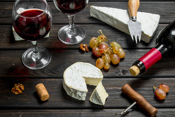 Brie cheese with red wine, nuts and grapes. On a wooden background. - Foto, Imagem