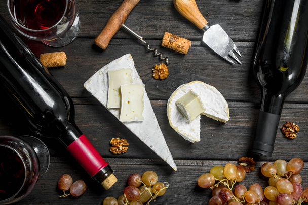 Brie cheese with red wine, nuts and grapes. On a wooden background. - 写真・画像