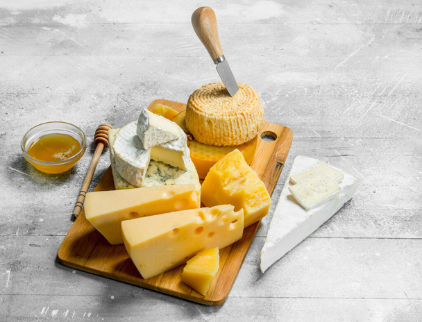 Different types of cheese with honey. On a rustic background. - 写真・画像