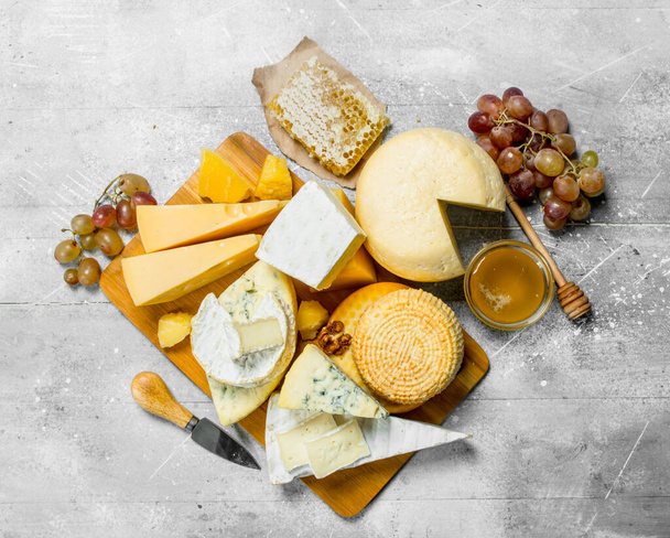 Different kinds of cheese with honey and grapes. On a rustic background. - Foto, Bild