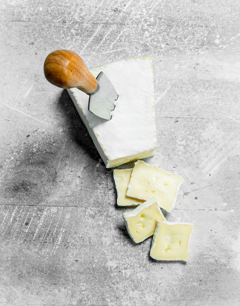 Brie cheese with knife. On a rustic background. - Foto, Imagen