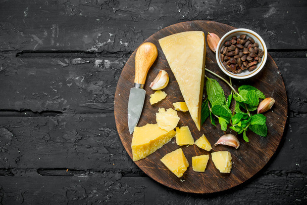 Parmesan cheese with garlic, pine nuts and mint leaves. On black rustic background. - Photo, image
