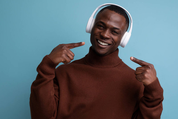 positive young African music maker with white headphones. - Foto, immagini
