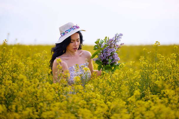 portrait d'une femme brune dans un champ de colza au printemps - Photo, image