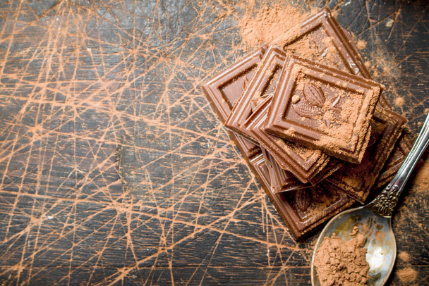 Chocolate slices with cocoa powder. On a wooden background. - 写真・画像