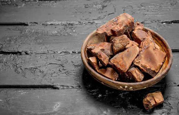 Crushed dark chocolate in a bowl . On black rustic background - 写真・画像