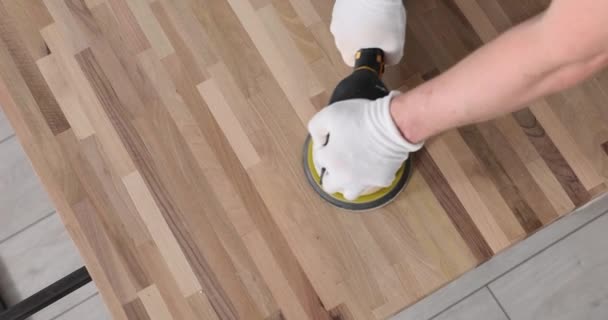 Férfi szakértő kesztyűk feldolgozásában parketta köszörűgéppel a házban. Professzionális alkalmazott kezei egyszerű fa felületen, lassított felvételen - Felvétel, videó