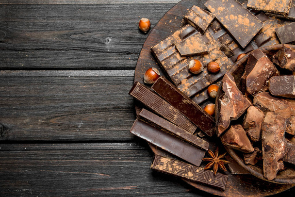 Assortment of different chocolate with nuts and cinnamon. On a wooden background. - Photo, Image