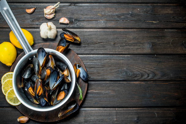 Fresh seafood clams with lemon and garlic. On a wooden background. - Photo, Image