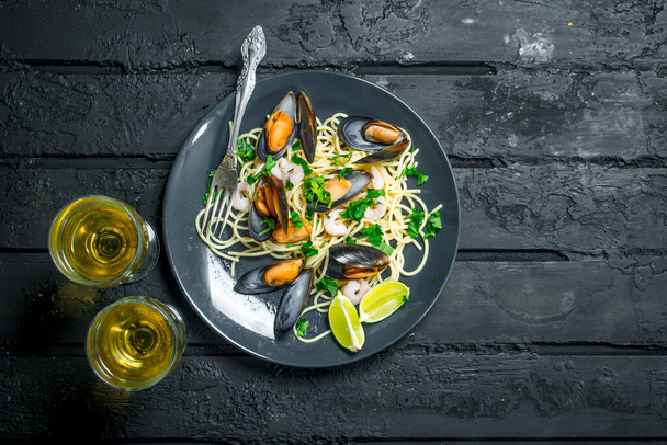 Mediterranean food. Seafood spaghetti with clams and white wine. On a black rustic background. - Photo, Image