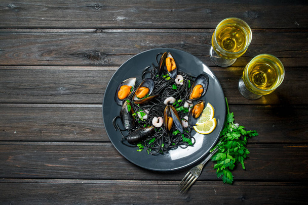 Mediterranean food. Spaghetti with cuttlefish ink, clams and white wine. On a wooden background. - Foto, imagen