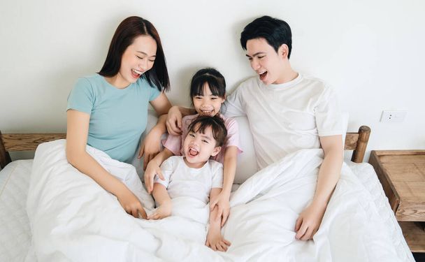 jong aziatisch familie op bed - Foto, afbeelding