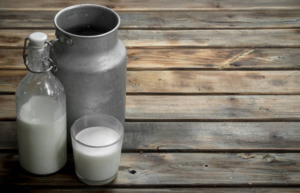Fresh milk in a glass with a can. On a wooden background. - Photo, Image