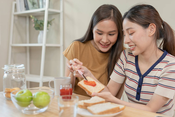 HLBT:tä. Aasialainen lesbo pari hymyilee ja osoittaa rakkautta syödessään aamiaista kotona. Nuori aasialainen pari halaamassa toisiaan onnellisesti, rakastavaiset, homoseksuaalisuus, homoseksuaalisuus, vapaus, ilmaisut - Valokuva, kuva
