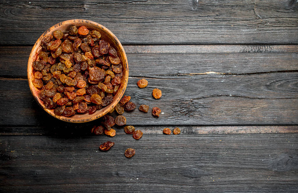 Raisins in bowl. On a wooden background. - Zdjęcie, obraz