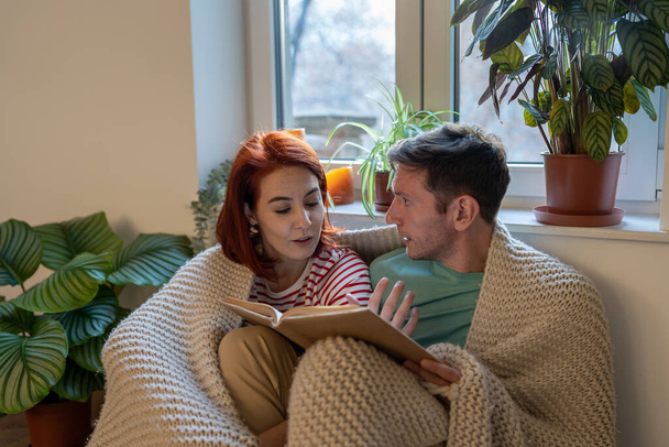 Молода сімейна пара чоловік і жінка обговорюють нову книгу, читаючи разом вдома, маючи спільні інтереси. Хобі для пар та інтелектуальна близькість у концепції стосунків
 - Фото, зображення