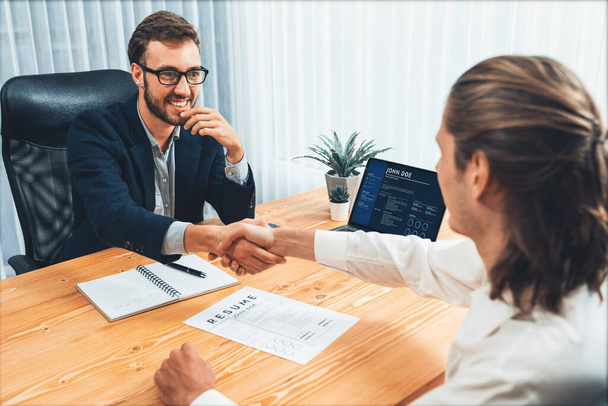 After successful meeting or job interview, two happy businessmen shake hands over resume papers. HR manager extend hand for congratulatory handshake to job applicant, welcoming new employee. Entity - Photo, Image